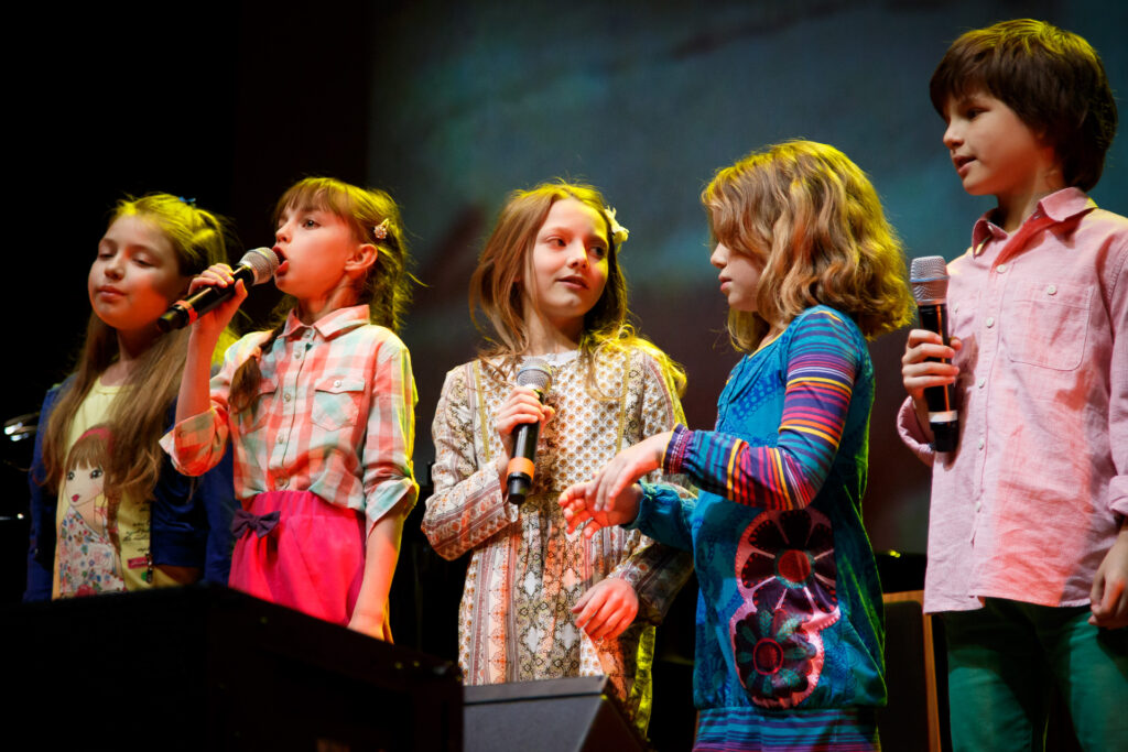 Grupa występujących dzieci, które śpiewają.