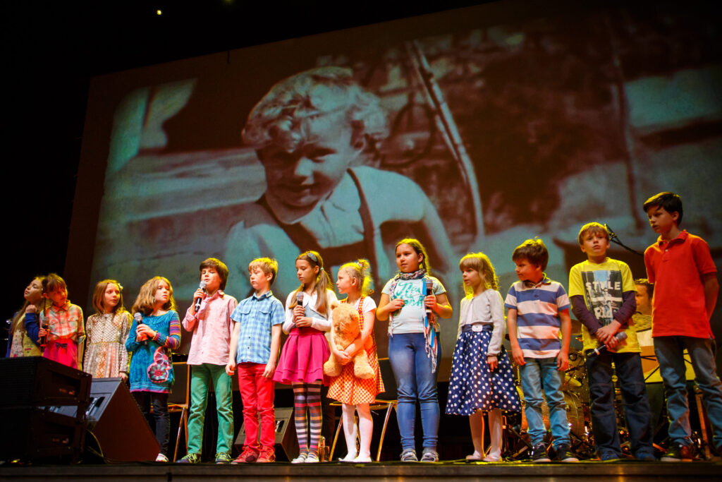 Grupa dzieci występujących na scenie. Dzieci śpiewają.