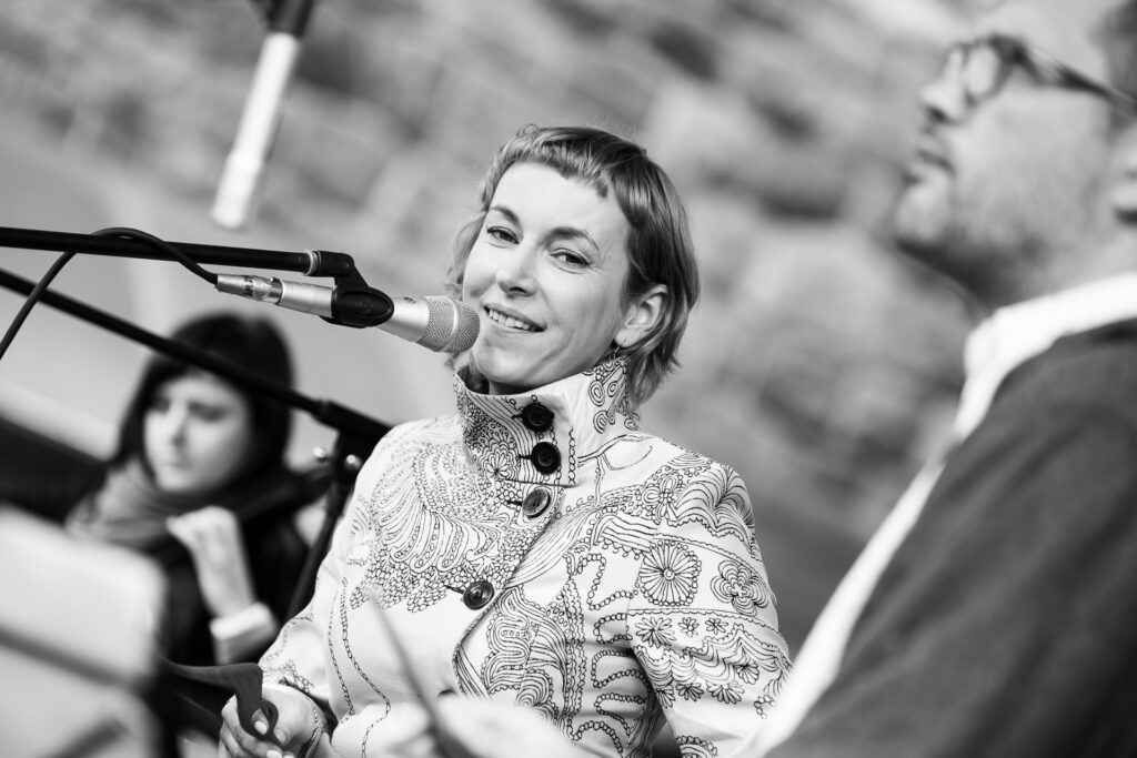 Zdjęcie czarno białe. Kobieta na scenie przed mikrofonem patrzy w bok