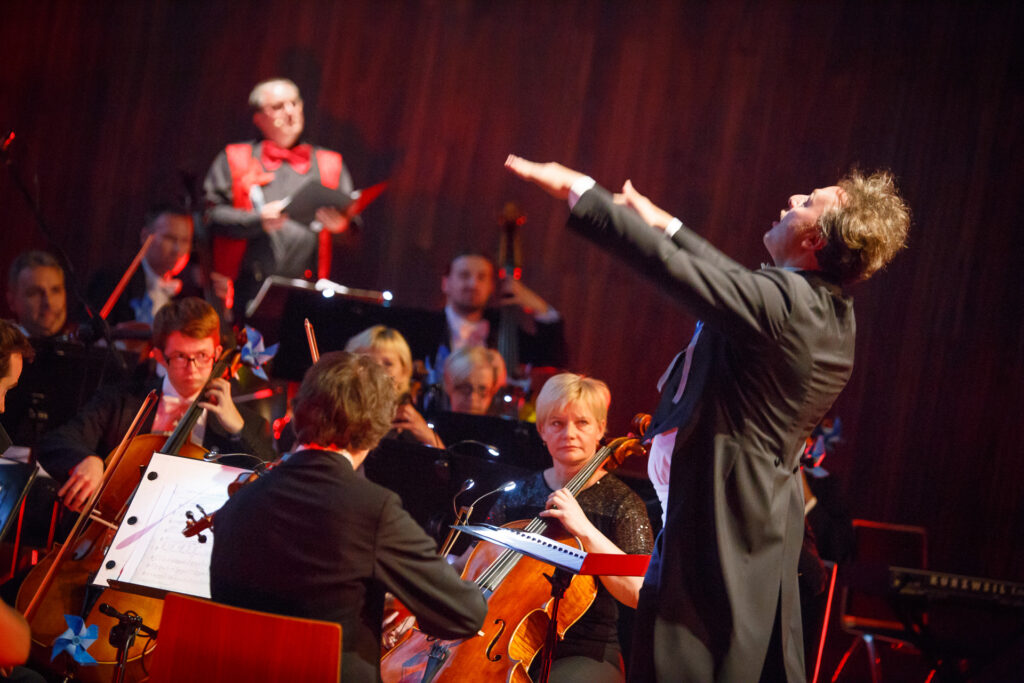 Na zdjęciu dyrygent z orkiestrą.