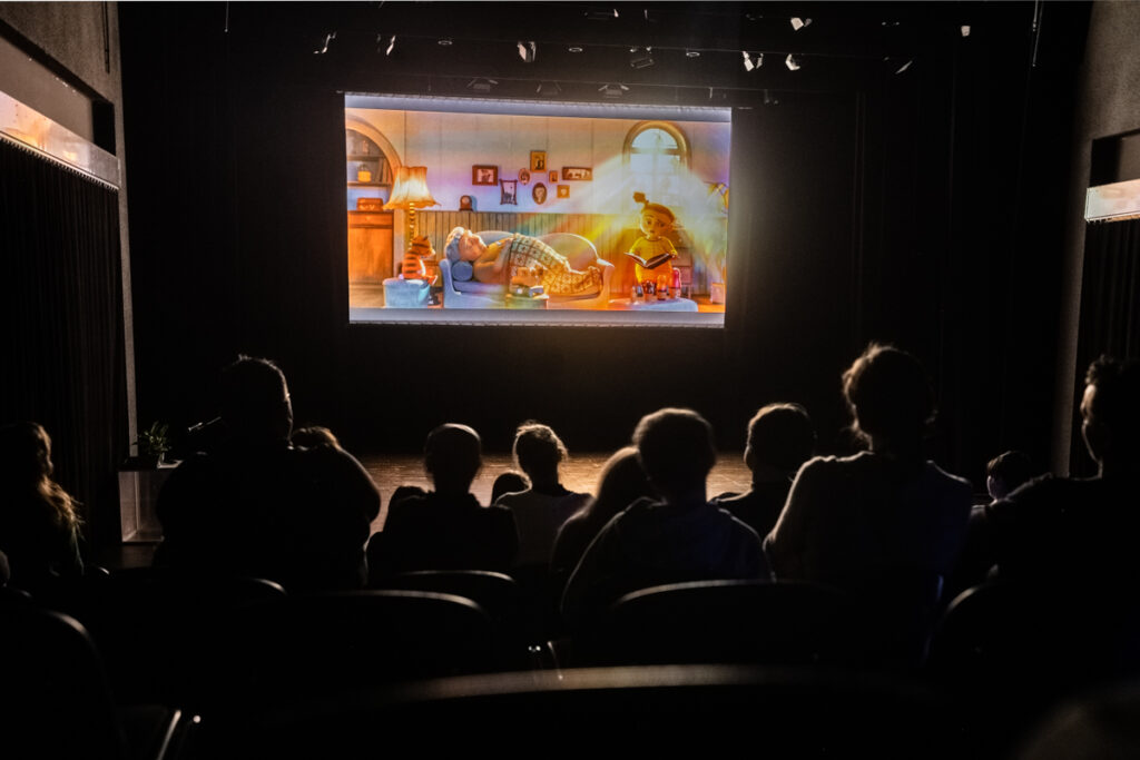 Osoby oglądają film wyświetlany na dużym ekranie.