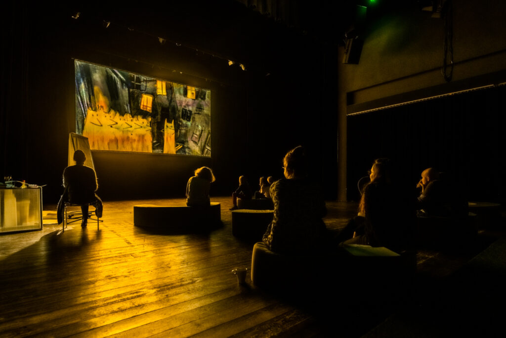 Osoby oglądają film wyświetlany na dużym ekranie.