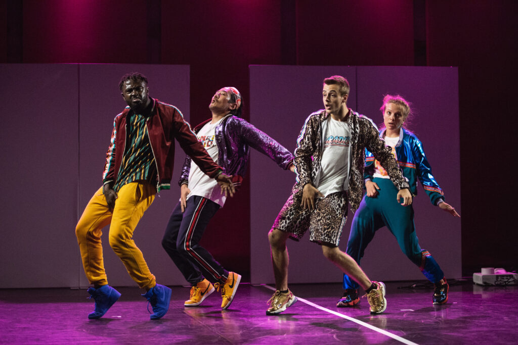 Czworo performerów na scenie w tanecznym ruchu.