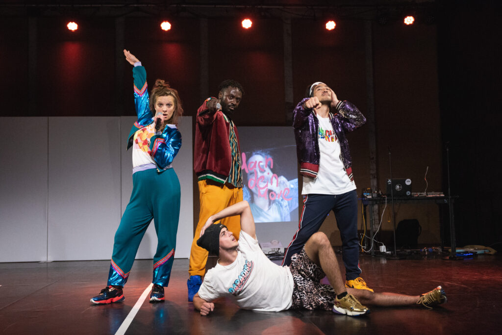 Trzy osoby stroją, jedna leży na podłodze.