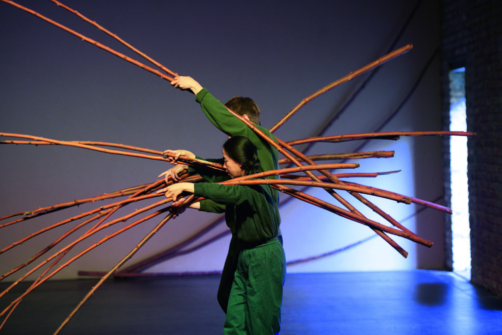 Kobieta i mężczyzna niosą na barkach długie wici wierzbowe.