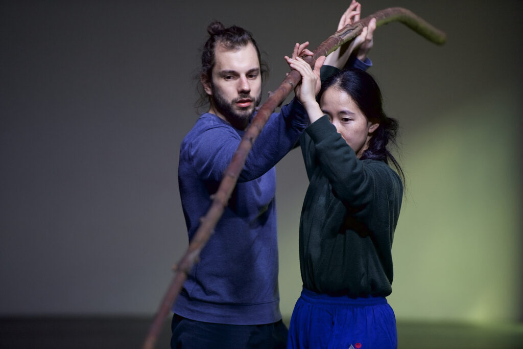 Mężczyzna i kobieta stoją na przeciwko siebie. Trzymają w dłoniach jedną długą wić wierzbową.