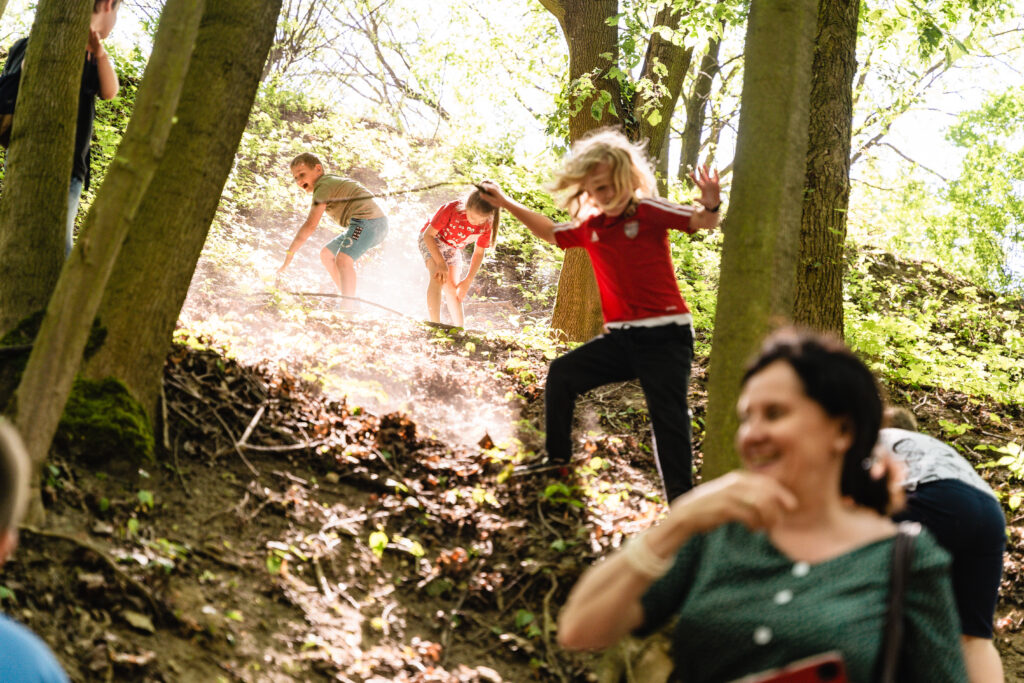 W lesie na zboczu bawi się grupa dzieci.