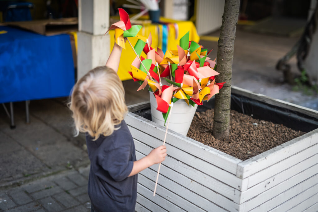 Dziecko sięga po kolorowe wiatraki.