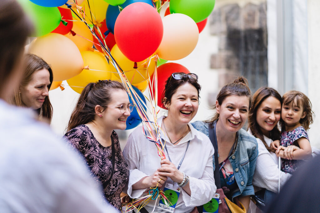 Grupa uśmiechniętych kobiet. Jedna z nich trzyma pęk balonów.