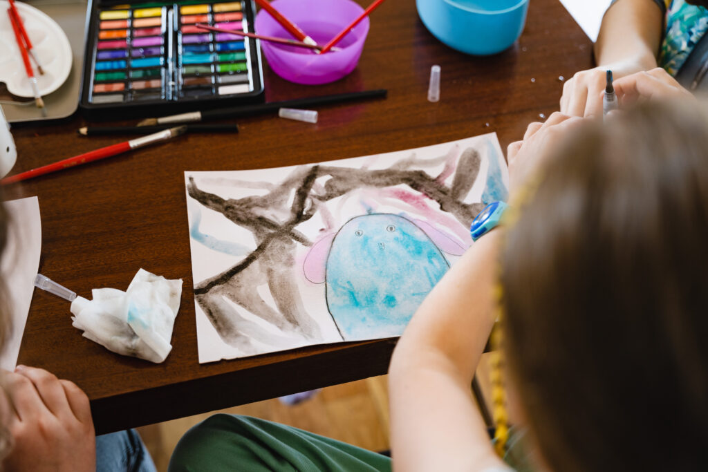 Na stole rysunek przedstawiający kolorową, fantastyczną postać.