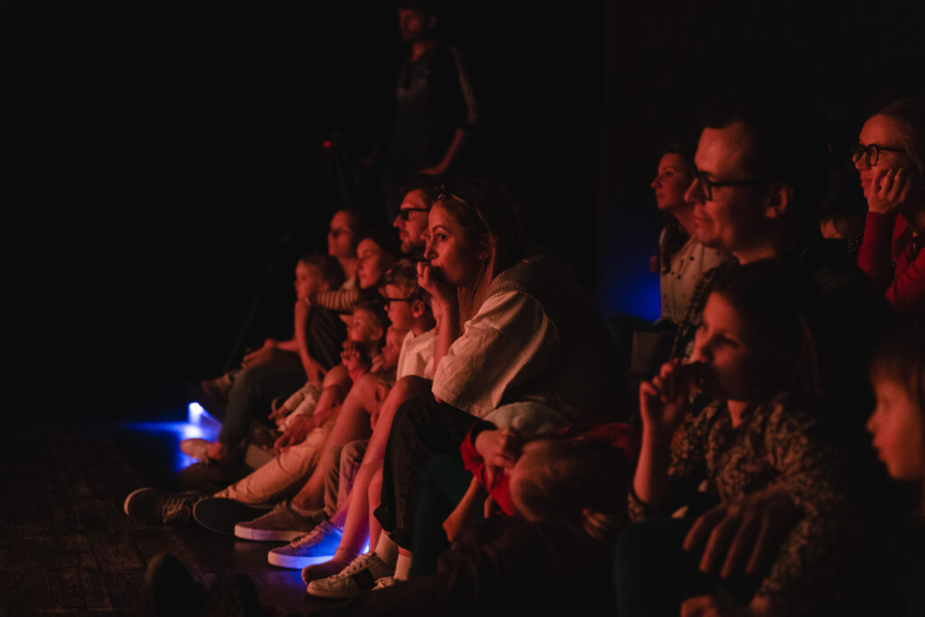 Osoby na widowni wpatrzone w przedstawienie.