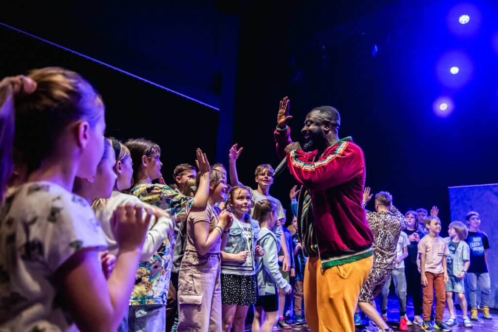 Aktor przybija piątkę grupie dzieci.