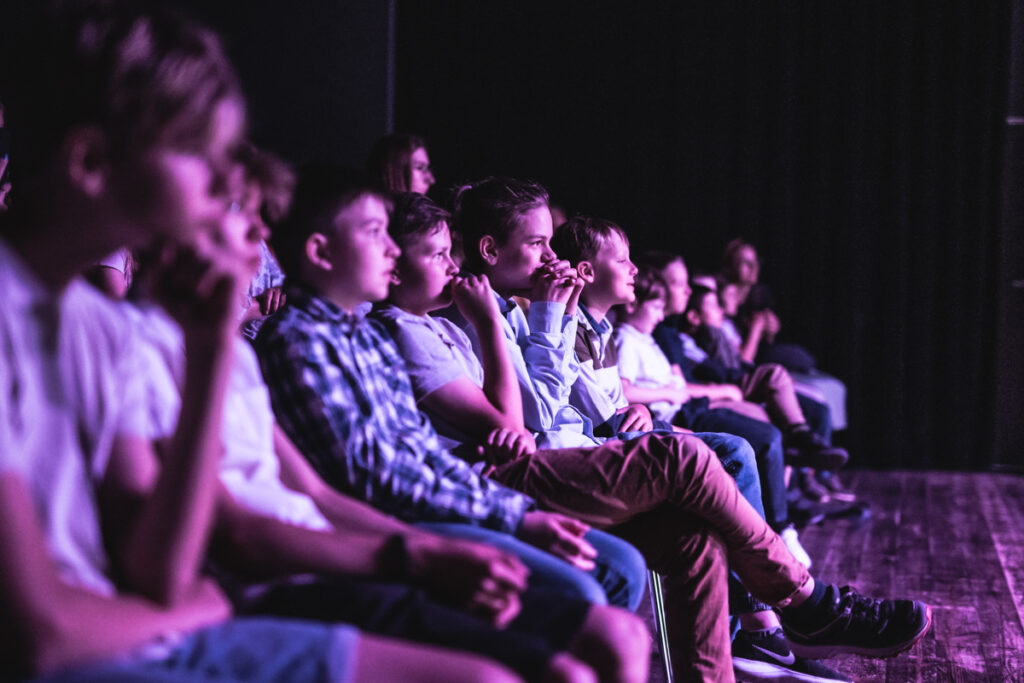 Grupa dzieci wpatrzona z przejęciem na scenę.