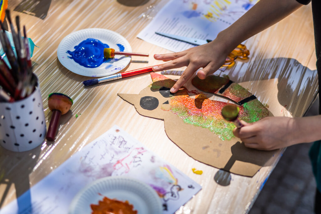 Dziecko maluje i ozdabia kartonowego kota.