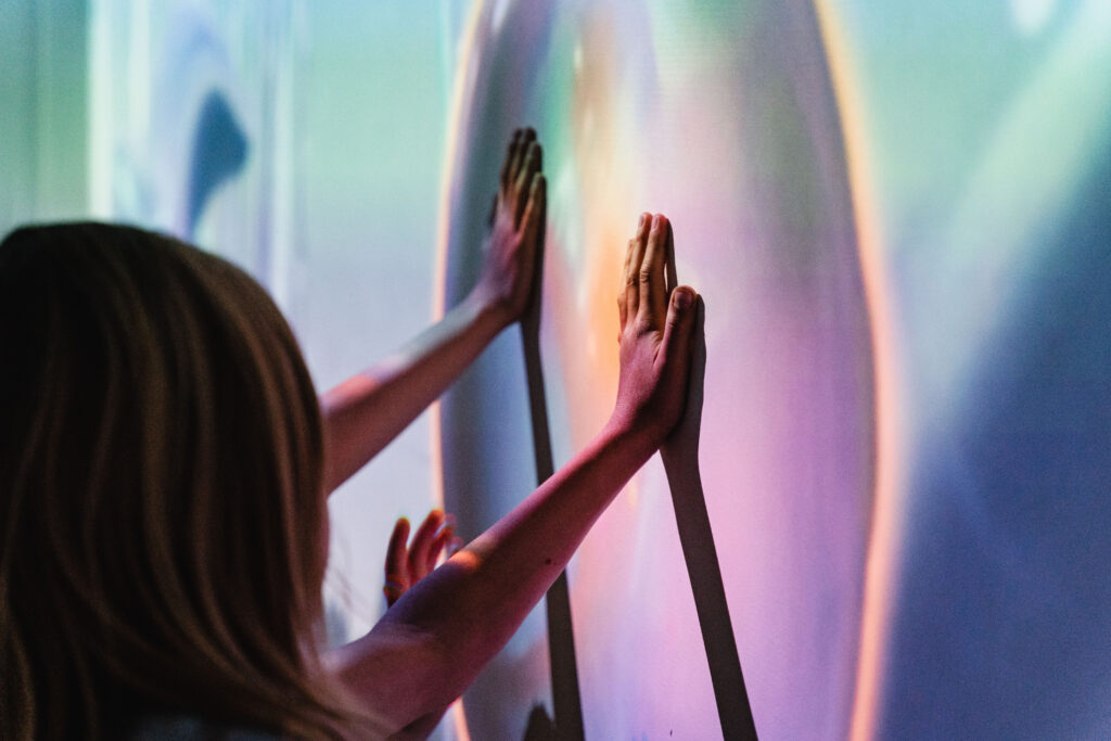 Po prawej ściana, na jakiej widać kolorowy obraz. Dwójka dzieci dotyka rękami ściany.