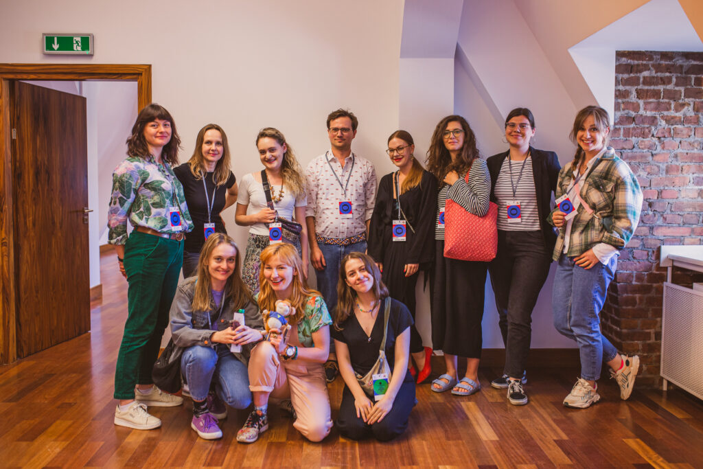 Grupa osób stoi lub klęka w sali. Pozują do zdjęcia.