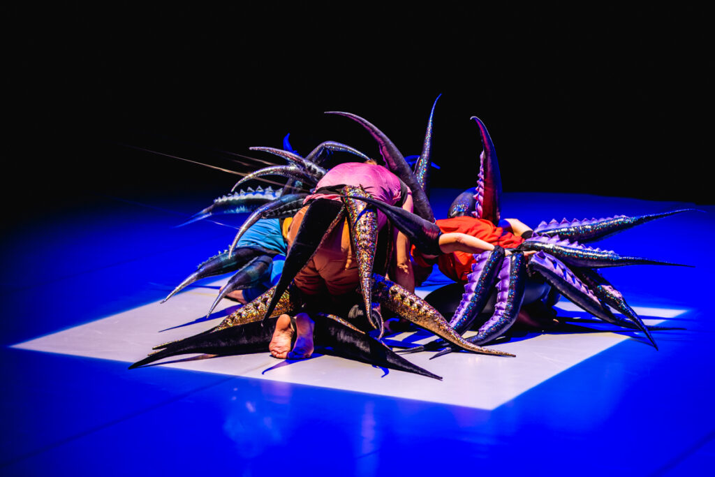 Na scenie. Troje aktorów klęczy na podłodze. Są zwróceni. Z różnych części ciała wyrastają długie ogony.