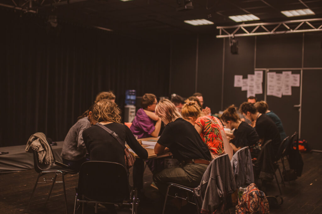 Osoby siedzące przy stole podczas działań warsztatowych