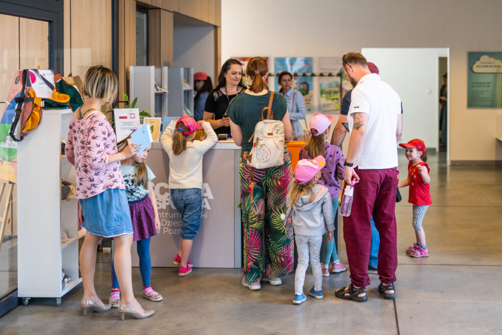 grupa dzieci stojących tyłem, zwrócona ku kasie w Scenie Wspólnej