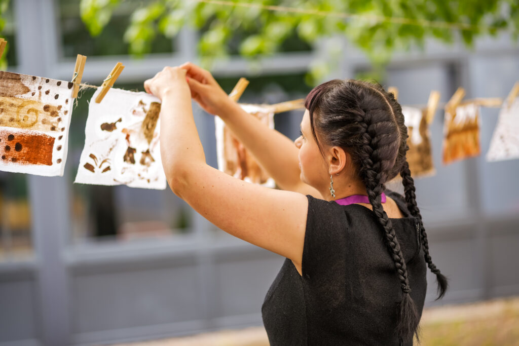 osoba wieszająca prace plastyczne na sznurku