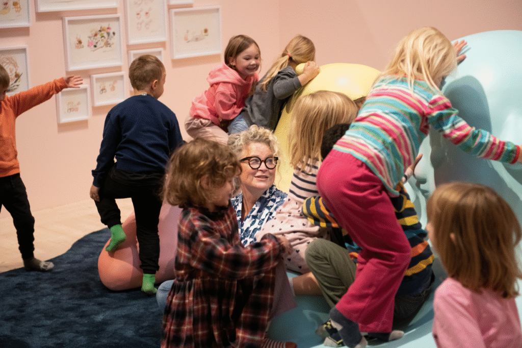 Osoba Stiny Wirsén podczas zabawy na podłodze z ósemką dzieci