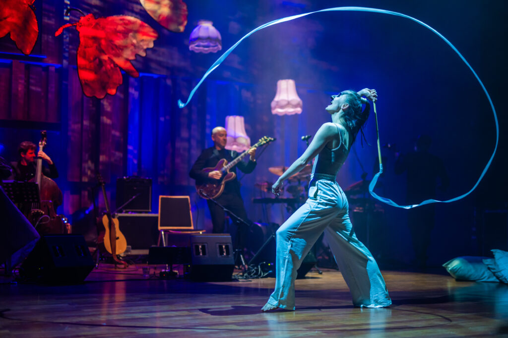 kobieta tańczy na scenie, w tle mężczyzna gra na gitarze