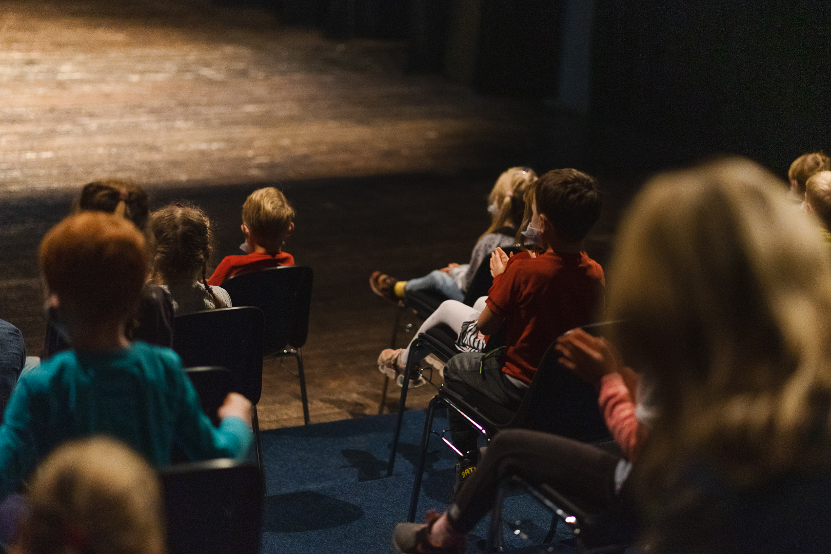 grupa dzieci siedzi na widowni w teatrze i ogląda spektakl