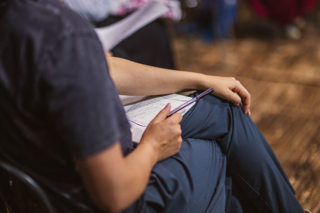 osoba siedzi na krześle, na kolanach ma notes z notatkami